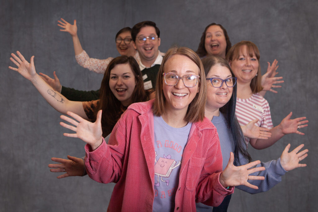 Youth library staff smiling and waving "jazz hands."