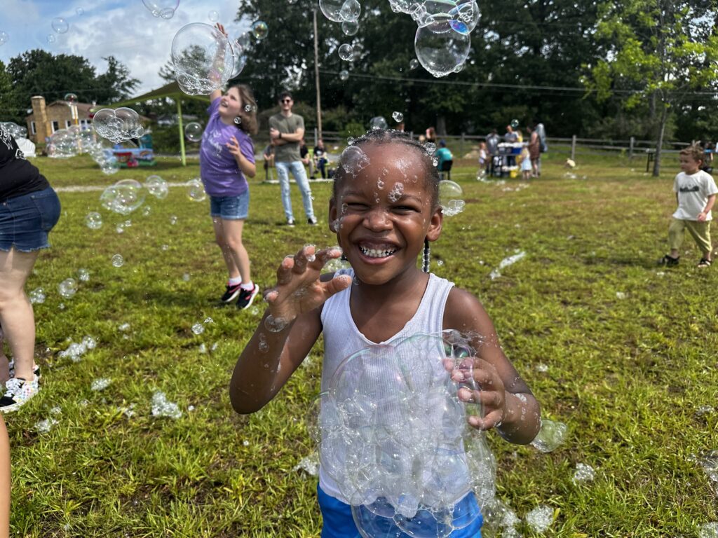 Young patron smiles big as they play with bubbles.