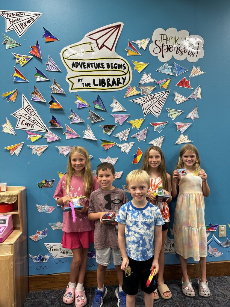 Young readers standing in front of a wall of "thank you" notes.