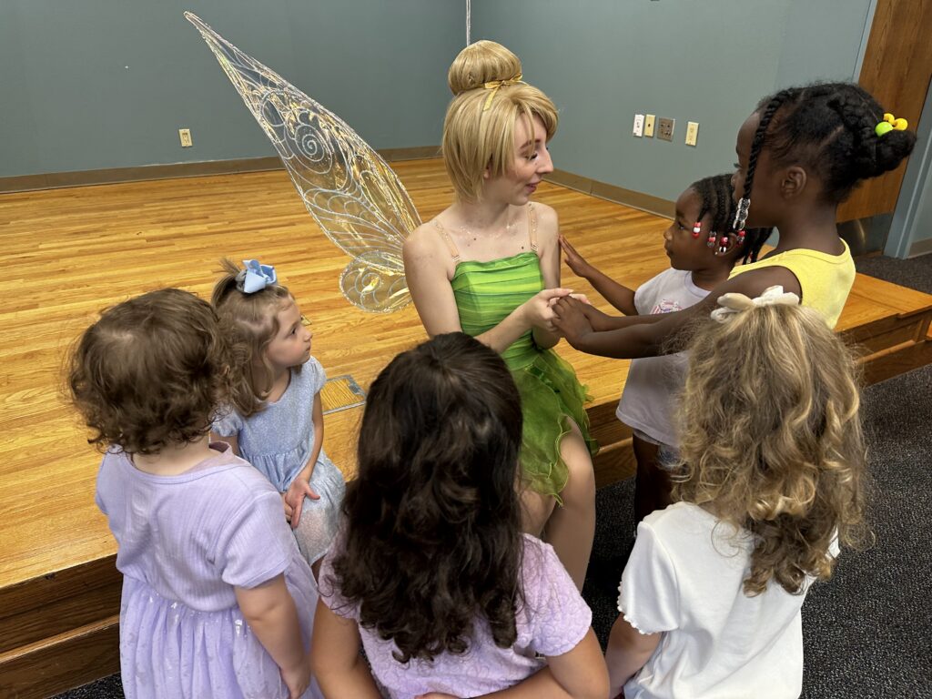 Young patrons gather around a person dressed as Tinker Bell.